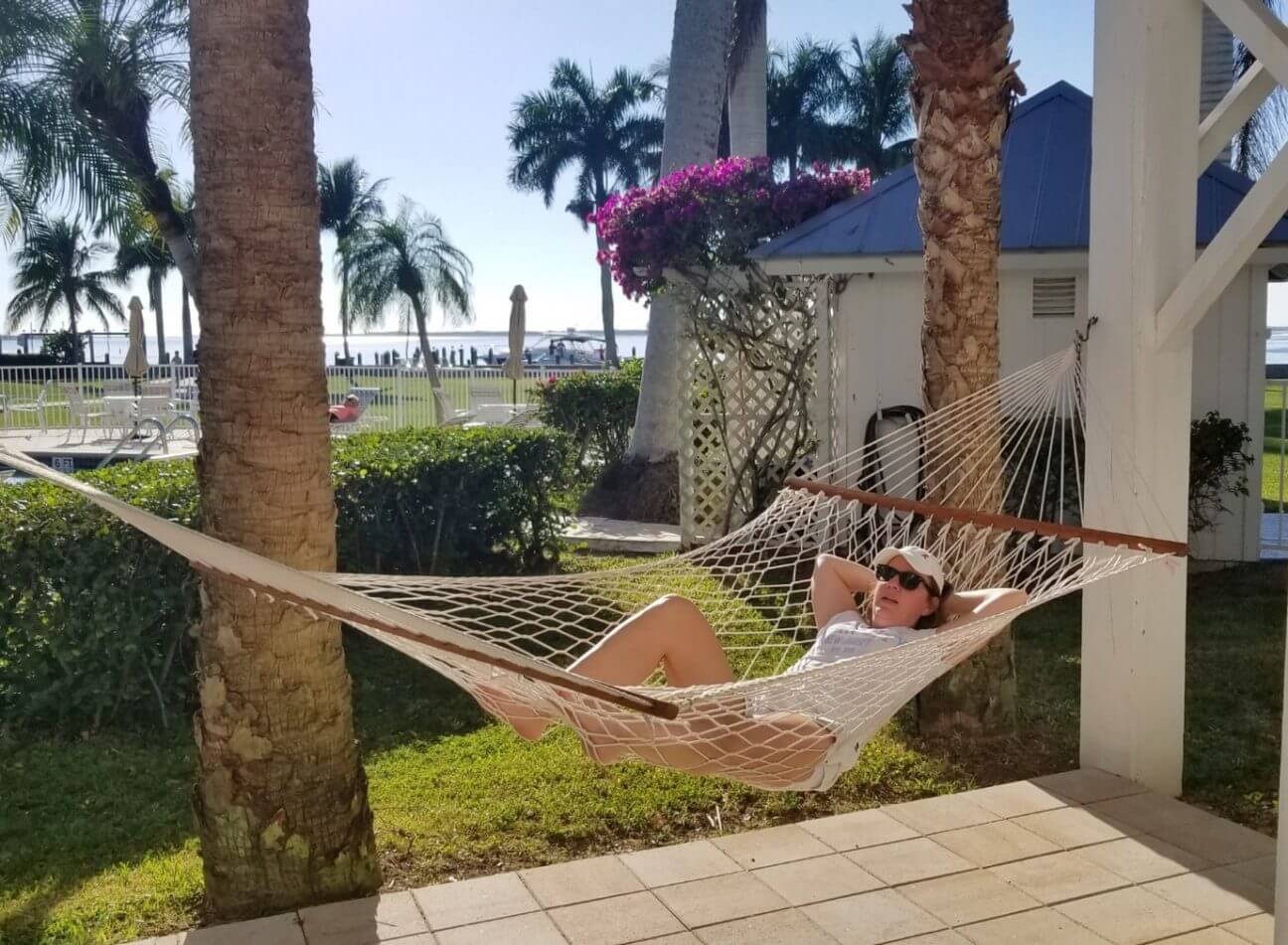 Woman reclines in a hammock beneath the Island House at Tarpon Lodge. 